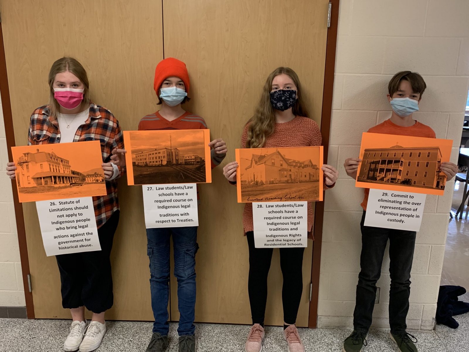 Students from Smiths Falls District Collegiate Institute hold pictures of residential schools with attributed Truth and Reconciliation Calls to Action Recommendations. 