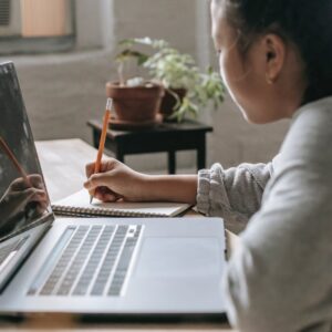 crop student at table with laptop and notebook