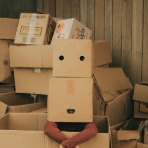 anonymous person with box on head near carton boxes