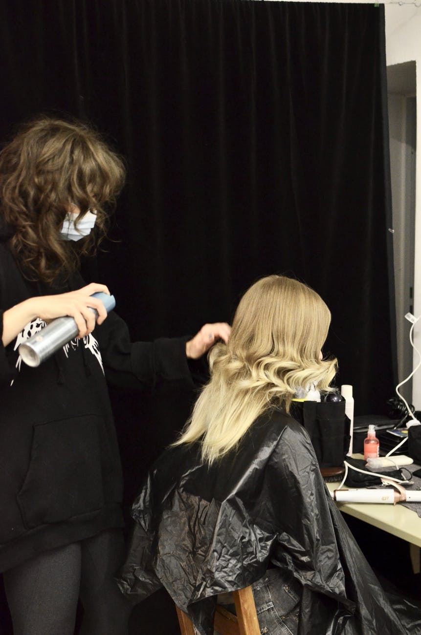 hairdresser making hairdo for client in dressing room