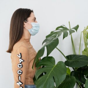 woman in brown sweater standing beside green plant