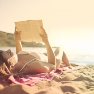 woman lying on beach reading book
