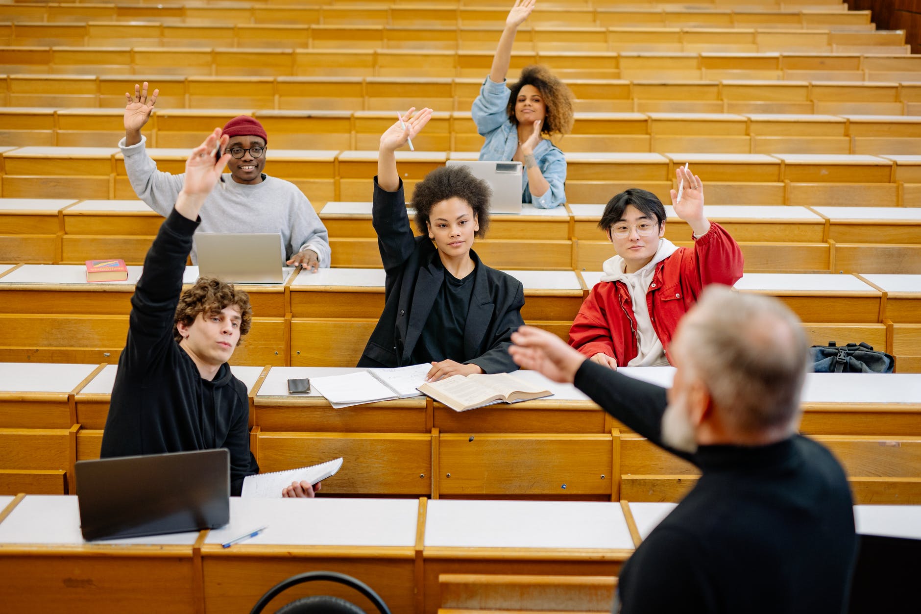 students raising their hands in a classroom