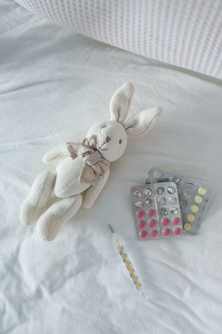 thermometer and pills on bed