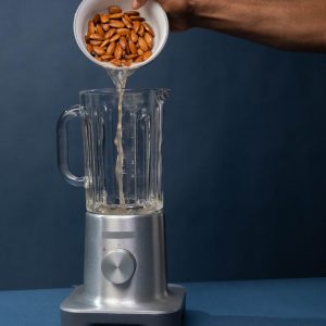 pouring of pecan nuts with liquid on a blender