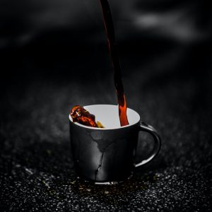 brown liquid pouring on black and white ceramic mug selective color photography