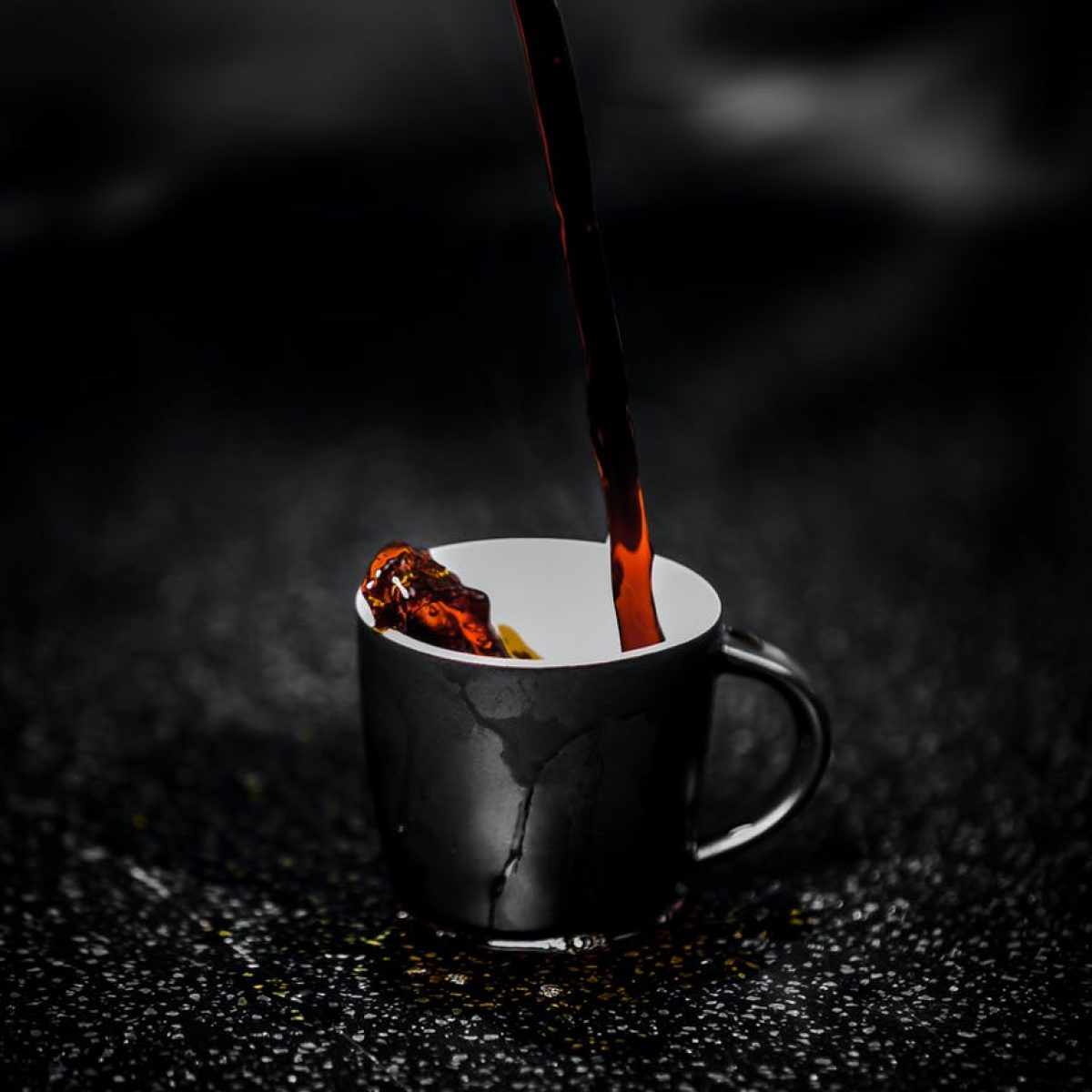 brown liquid pouring on black and white ceramic mug selective color photography