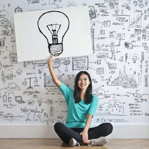 woman draw a light bulb in white board