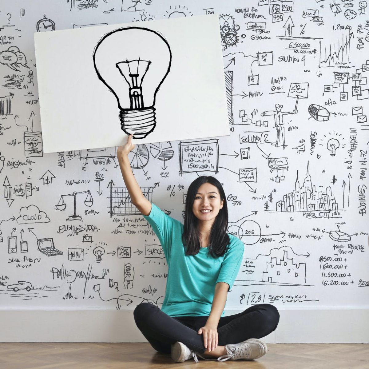 woman draw a light bulb in white board