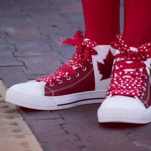closeup photo of person wearing white and red maple leaf printed lace up sneakers