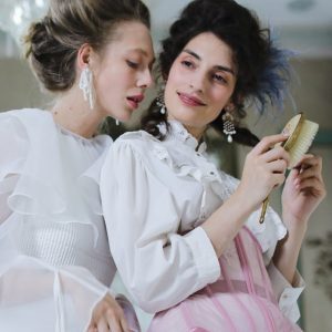 woman wearing white and pink dress brushing her hair beside woman in white dress