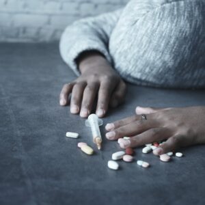 close up photo of person lying beside a syringe and tablets