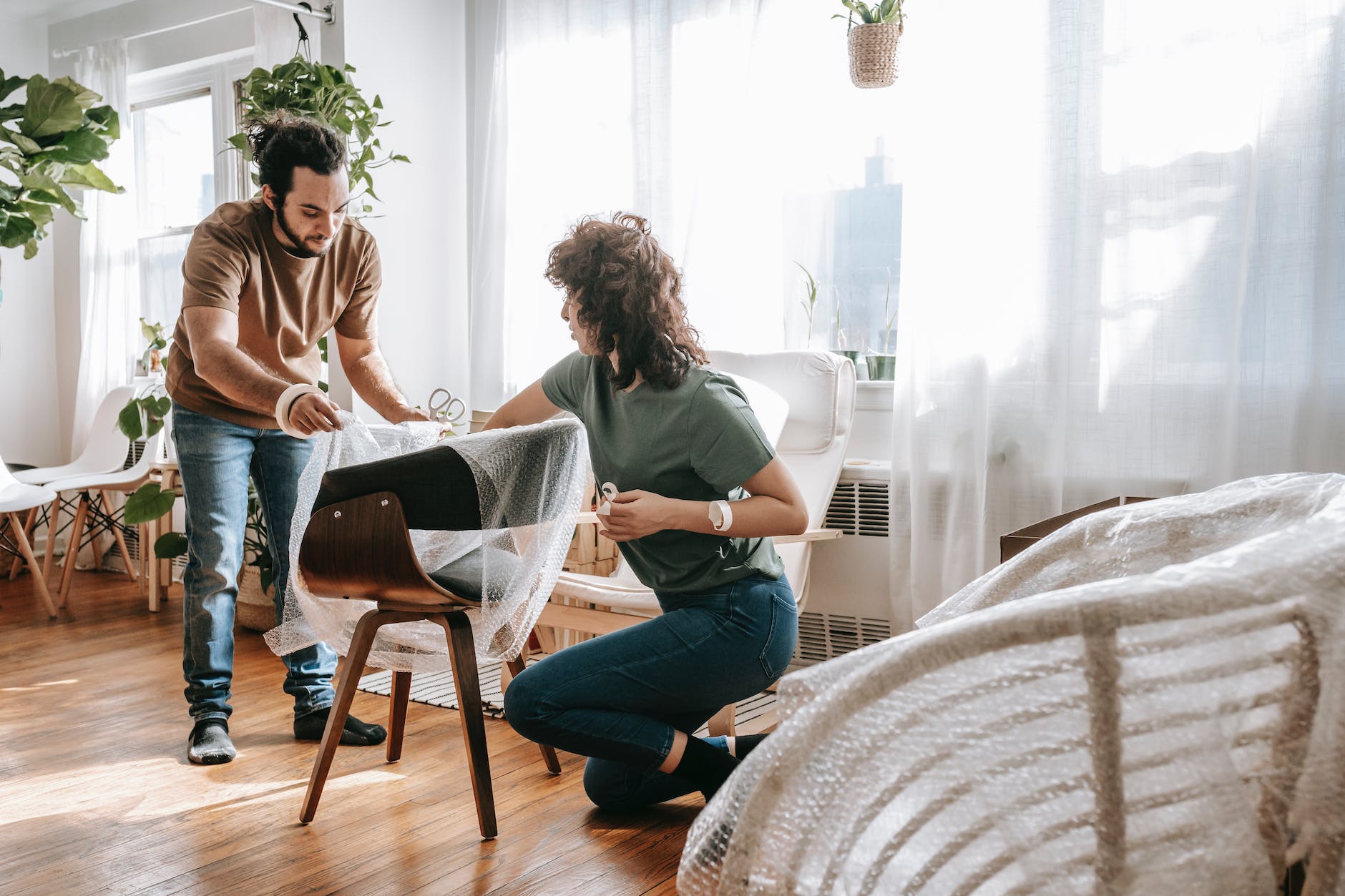 couple wrapping a chair with plastic