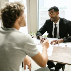 man in black suit jacket holding white paper