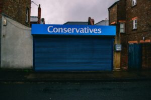 A blue closed shopfront with 'Conservatives' signage on a quiet urban street.