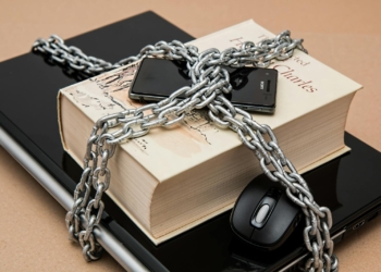 Chain-locked book, phone, and laptop symbolizing digital and intellectual security.