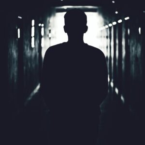 Silhouette of a person standing in a shadowy tunnel, evoking mystery.