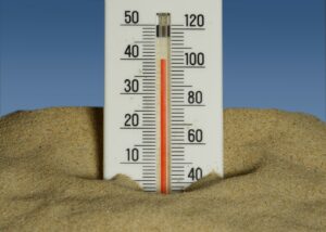 A thermometer in the sand with a blue sky in the background