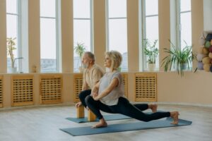 A senior couple practicing yoga indoors, focusing on a healthy lifestyle and flexibility.