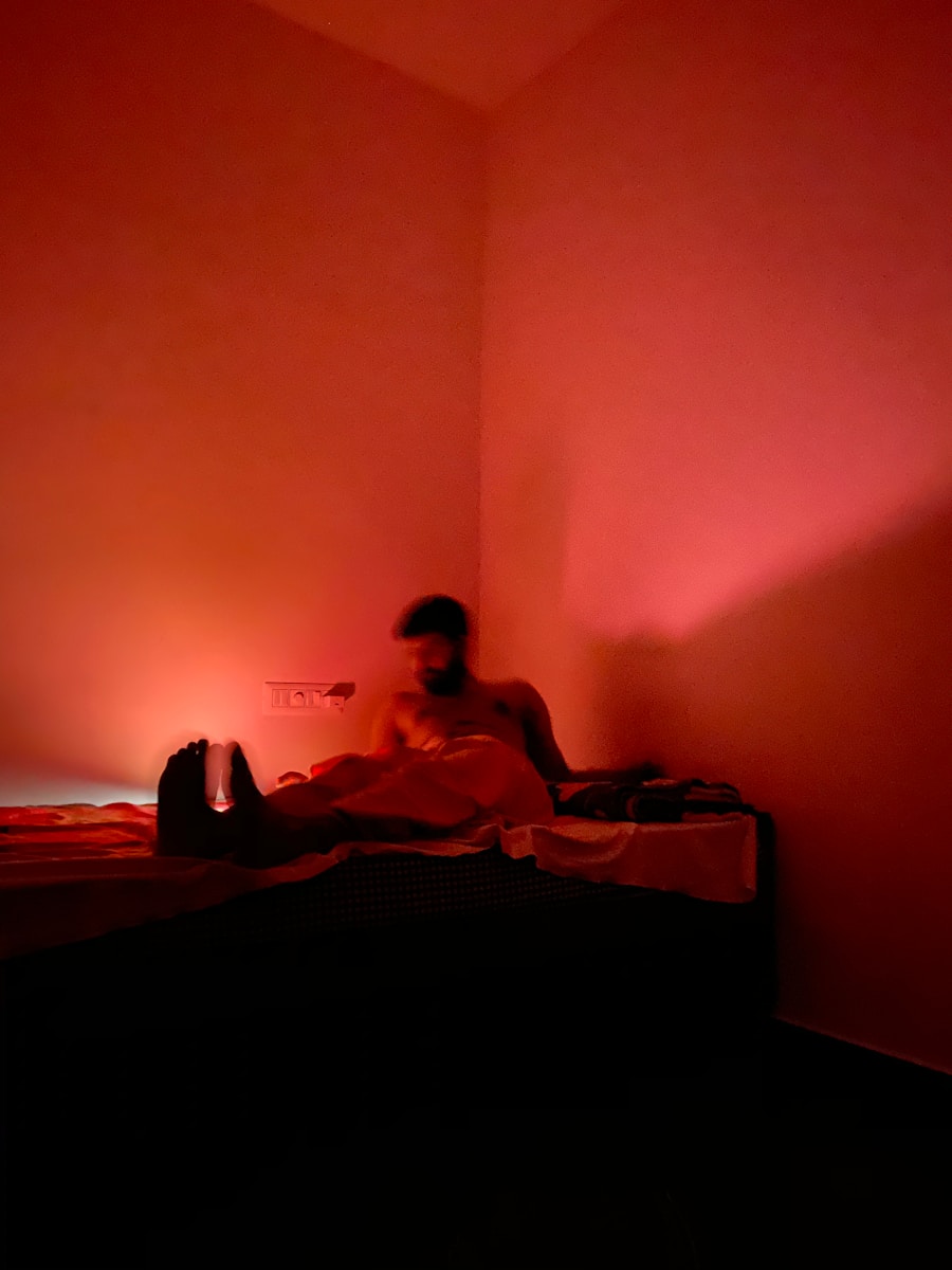 man in red t-shirt sitting on bed