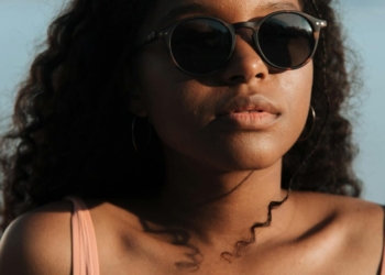 Close-up portrait of a woman wearing sunglasses enjoying a sunny day at the beach.