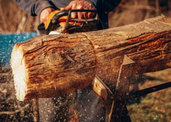a man using a chainsaw to cut a log