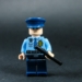 Lego police officer holding a baton against dark background