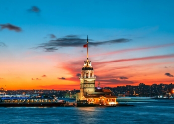 a large building with a flag on top of it next to a body of water