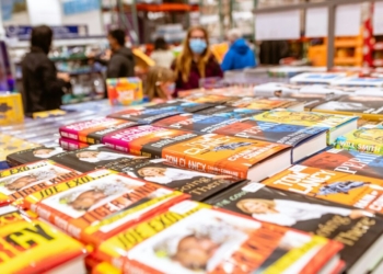 a table full of children's books with people in the background