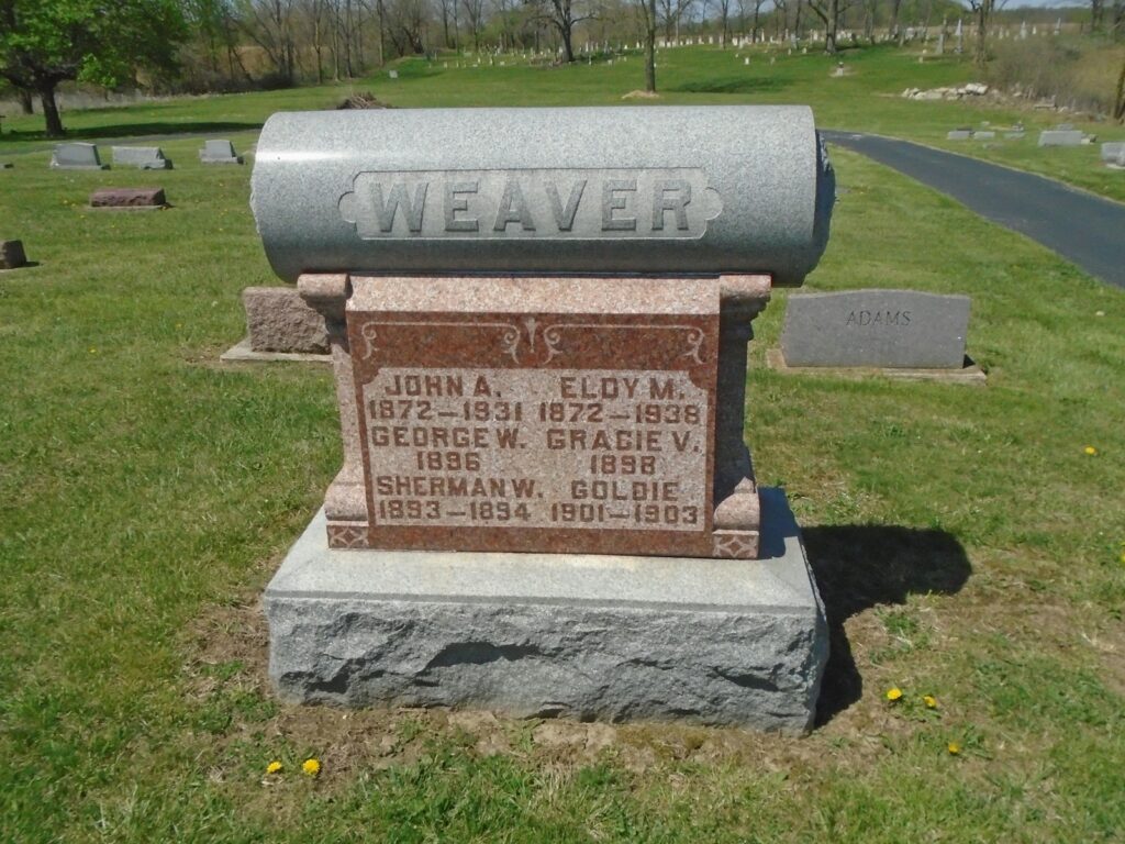 a headstone in the middle of a cemetery